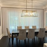 An elegant dining room with custom drapes hanging floor to ceiling.