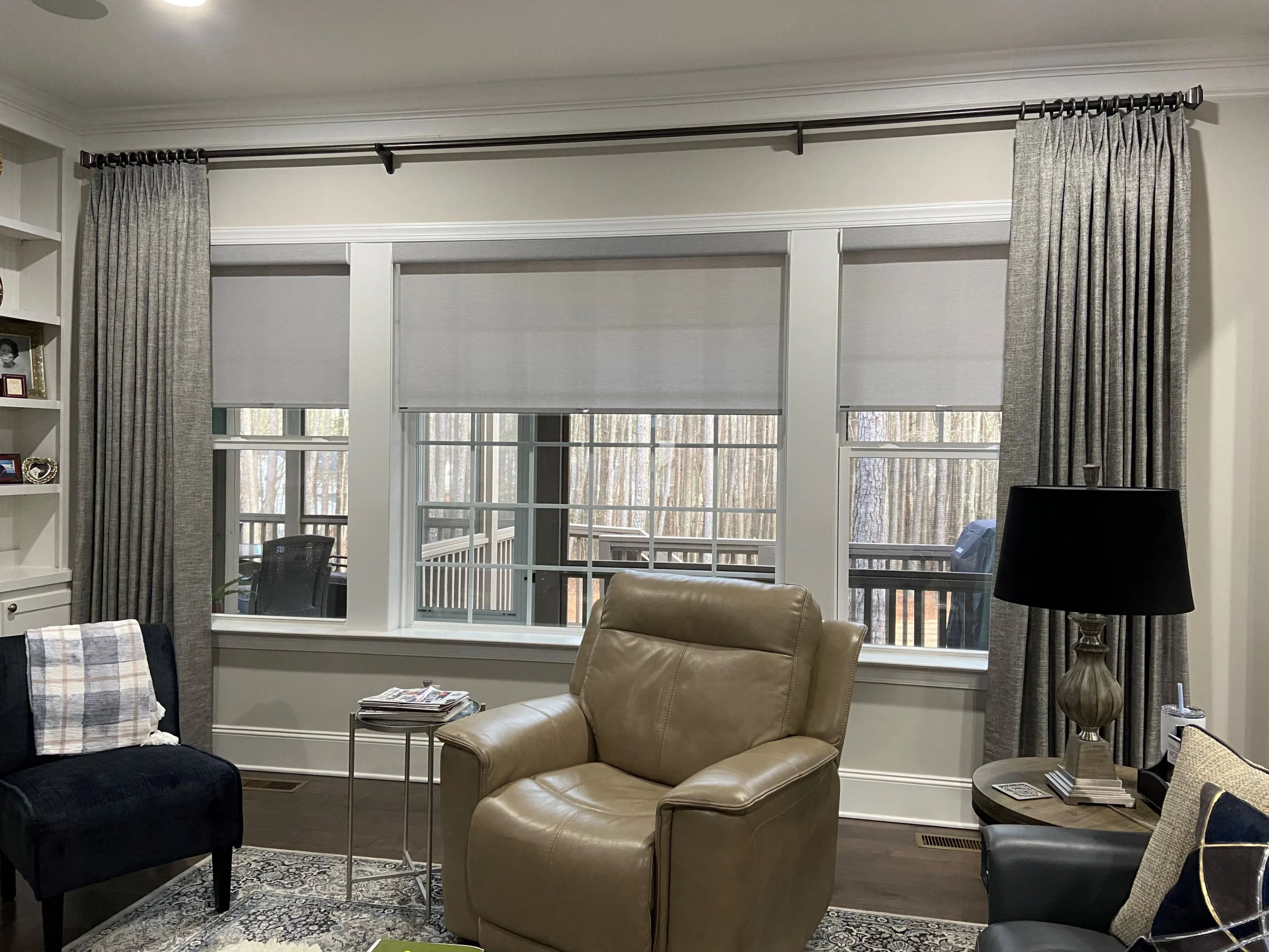 Living room with custom window treatments including solar shades and draperies